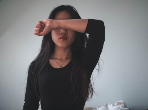Asian American woman puts her arm across her face