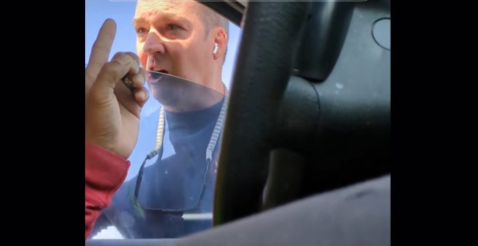 An angry firefighter is seen outside the driver side window confronting another motorist