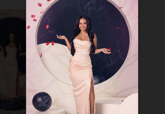 Jenn Tran in a long white gown standing in front of a circular shaped backdrop