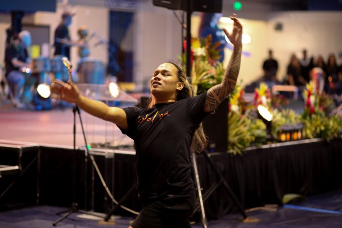 A man in a black shirt saying 'Ulalena dances on the gymnasium floor