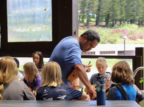 Reuben Pali helps a student strum chords on a Ukelele.