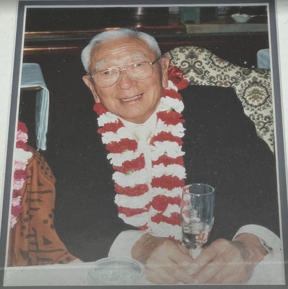 Kenge Takahashi, Nisei owner, Takahashi Market, wearing a scarf and coat with a glass of wine