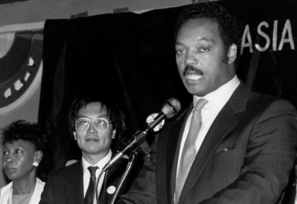 An exhausted Eddie Wong stands next to Jesse Jackson during a fundraiser  during the 1984 presidential campaign. 