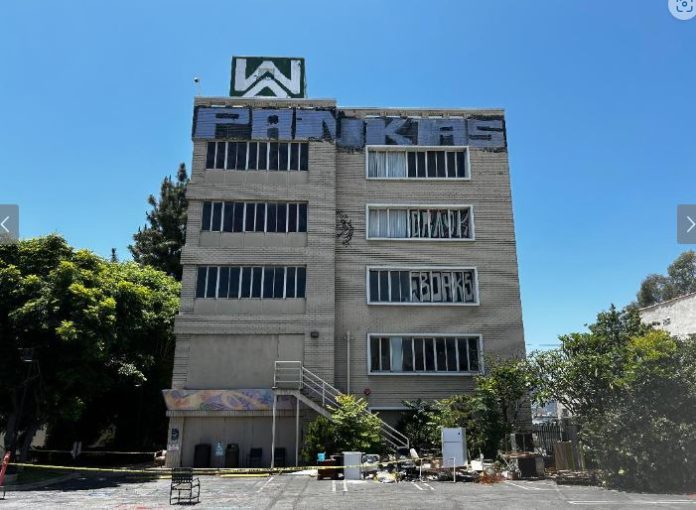 Photo from June 2024 taken of Sakura Senior Care Facility in Los Angeles show graffiti on the top of the building and abandoned furniture and refrigerator in the parking lot.