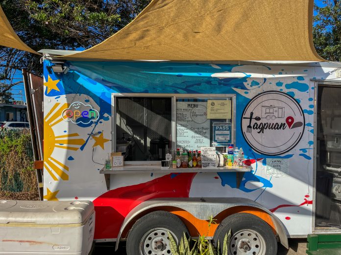 Tagpuan, a Filipino food truck. The front of the truck is decorated with the colors of the Filipino flag and a yellow sun.