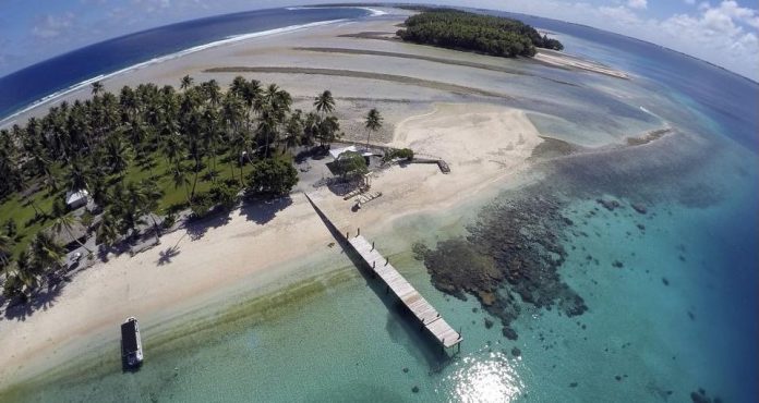 Evidence of Climate change on the Marshall Islands. An aerial photo shows a small section of the atoll that has slipped beneath the water line only showing a small pile of rocks at low tide on Majuro Atoll in the Marshall Islands in November 2015