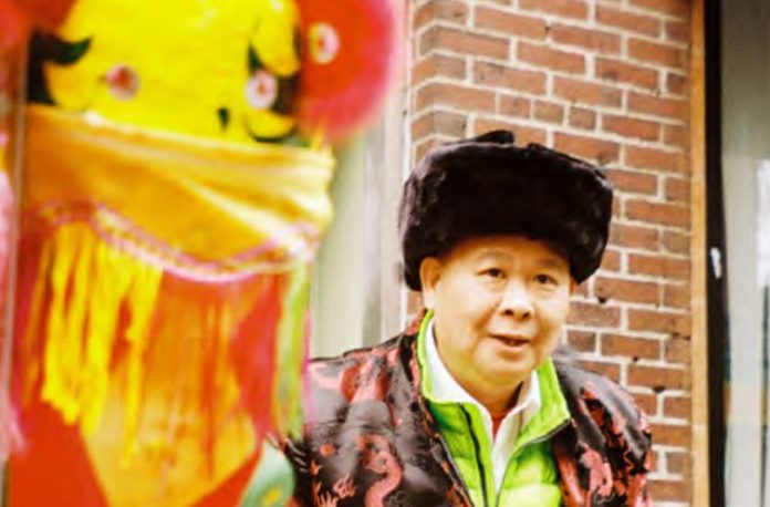 Photo of Chinese resident from Boston Chinatown standing next to a lion head