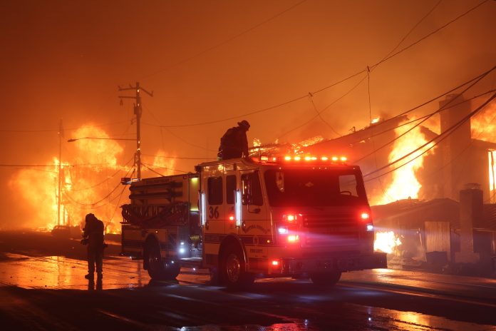 Silhouette of firefighter and fire truck battling Palisades Fire