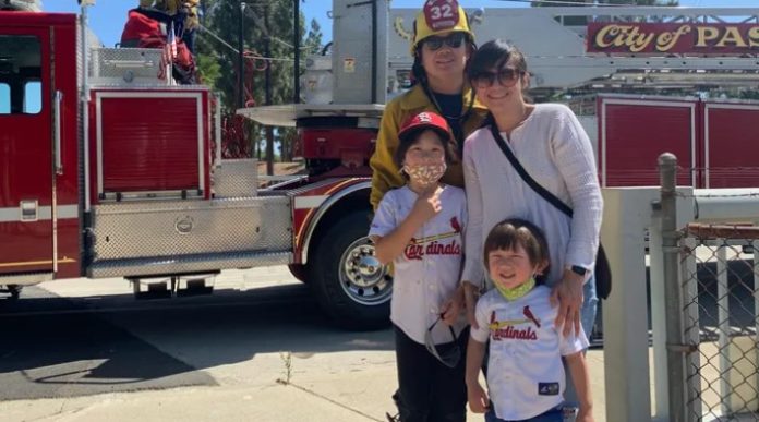 Chien Yu family photo with Yu in a fire hat and the family in front of a firetruck.