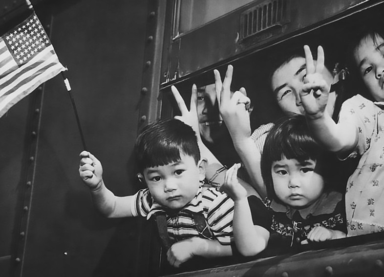 Group of young evacuees wave from special train as it leaves Seattle with Island evacuees, March 30, 1942