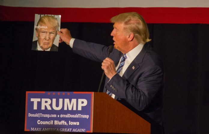 Then Presidential candidate Donald Trump holds up a magazine cover featuring himself while at a campaign stop at the Mid-America Center in Council Bluffs, Iowa