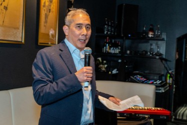 Donald Young speaks while holding a microphone in one hand and papers in another.